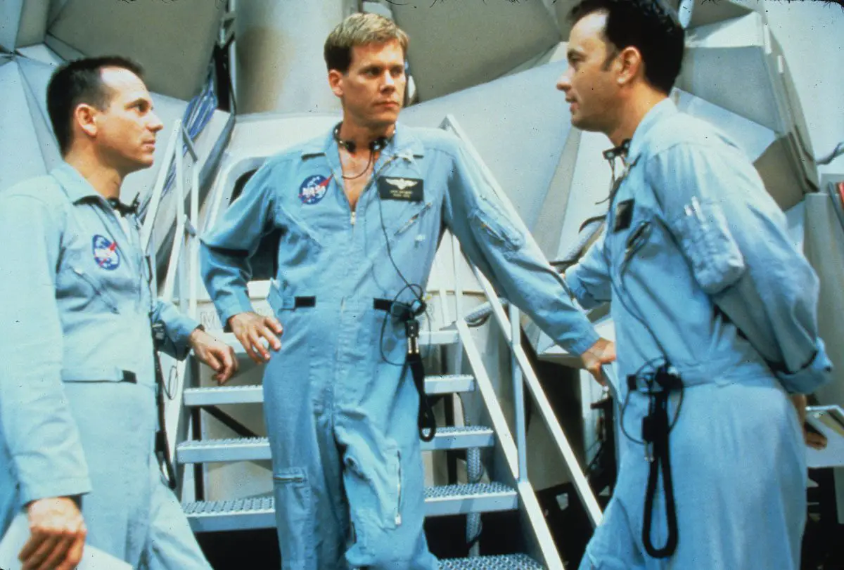 the three crew members, lovell, swigert, and haise, stand at the base of a staircase talking