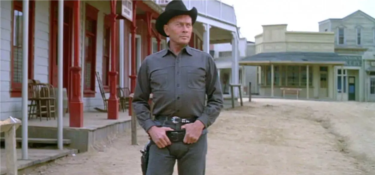 The Gunslinger stands in the road with his hands in his gun belt.