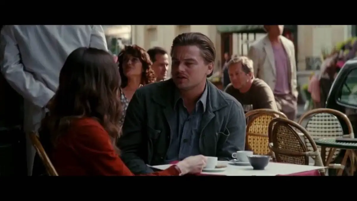 Leonardo DiCaprio and Ellen Page talking at a table outside a cafe in Inception