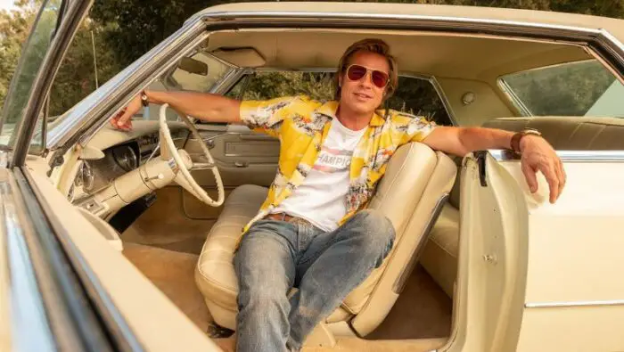 Brad Pitt sits in his car with a yellow Hawaiian shirt