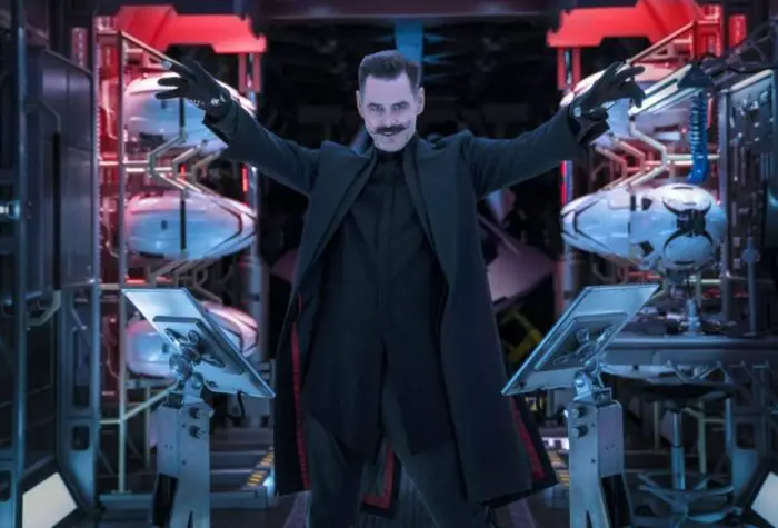Dr. Robotnik raises his arms in a small room surrounded by drones