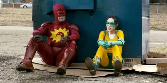 A man and a young woman are sitting dressed as superheros sat in front of a bin