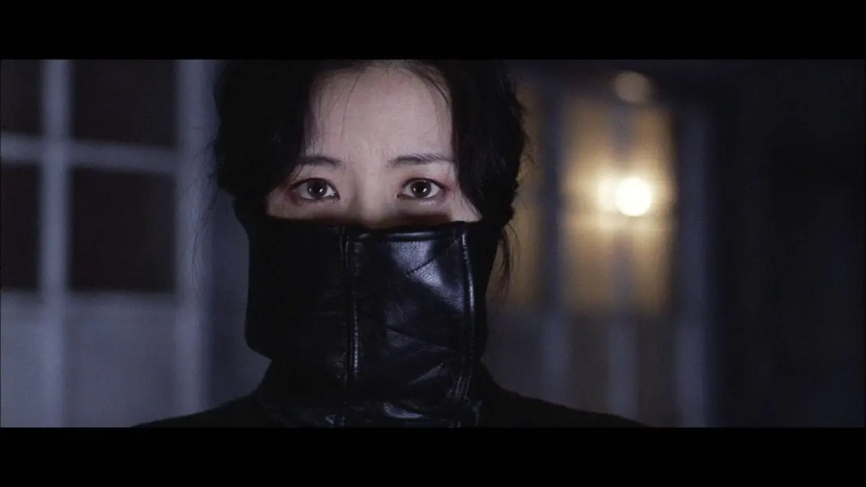 CU of Geum-ja with her high leather collar covering half of her face