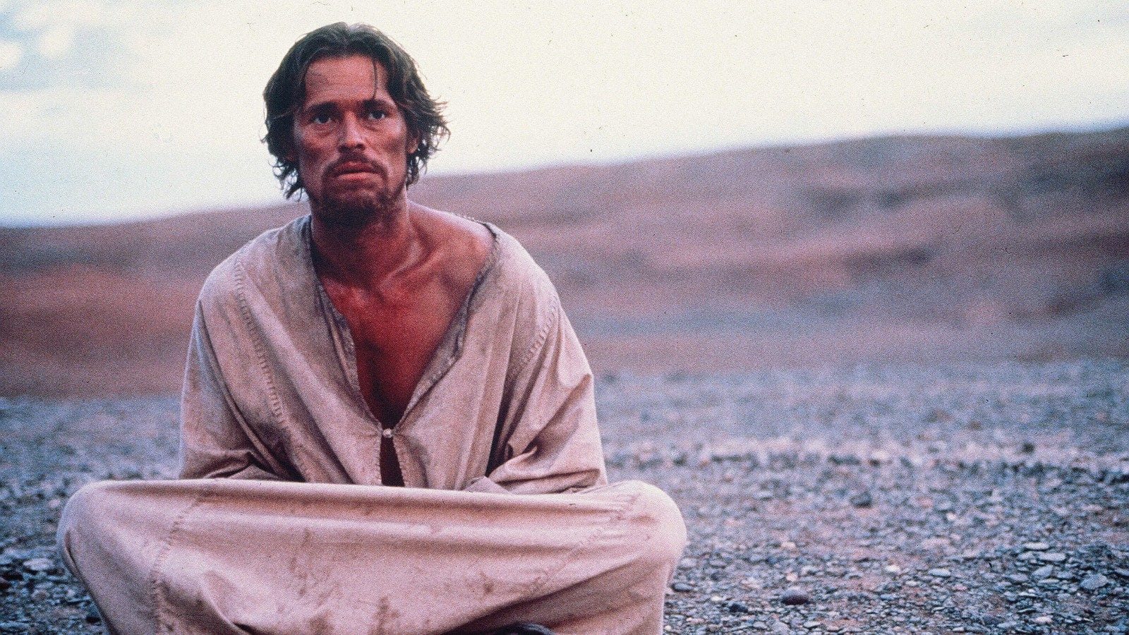 Jesus, looking haggard, sits alone in the desert