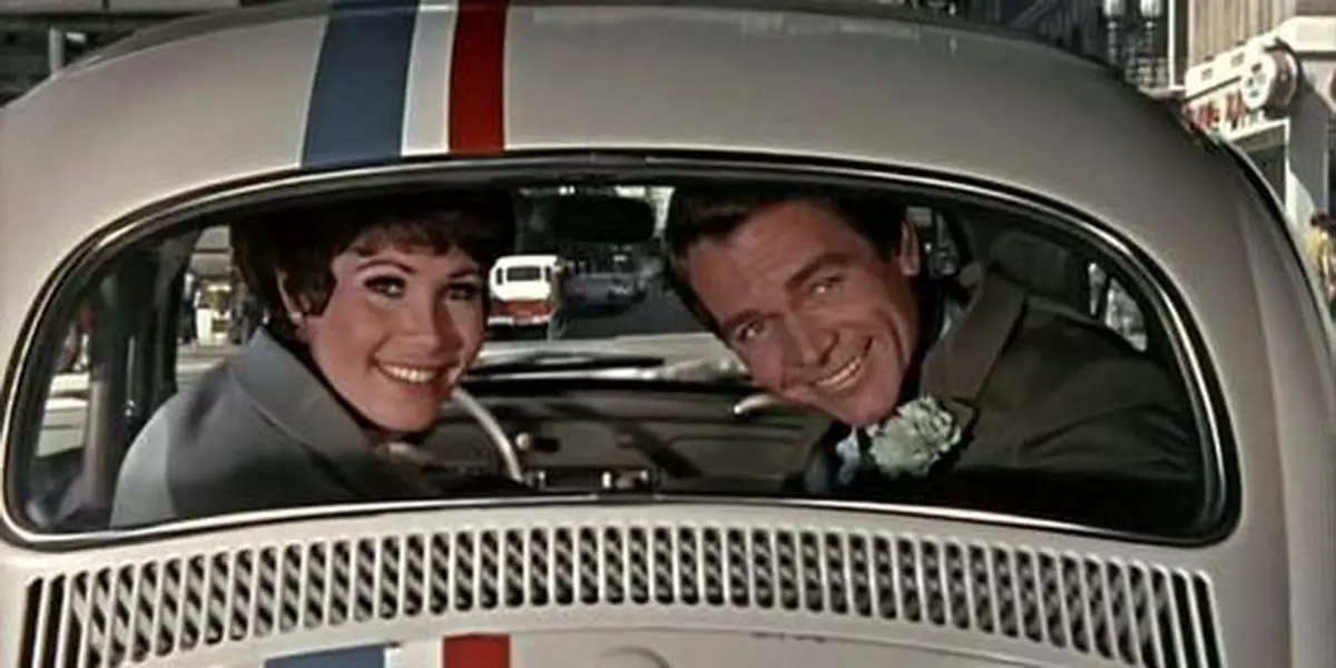 Carole and Jim smiling from Herbie's backseat and looking behind them 