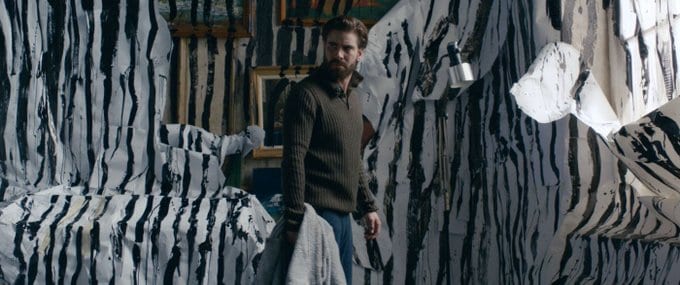 Matt holds a piece of blanket while surrounded by painted, destroyed walls