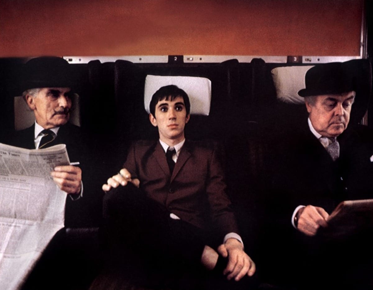 An out-of-sorts Jimmy sits between two stuffy businessmen on the train