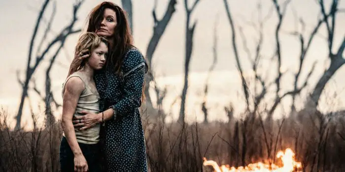 Ellen Kelly hugs her son Ned outside next to a small fire.