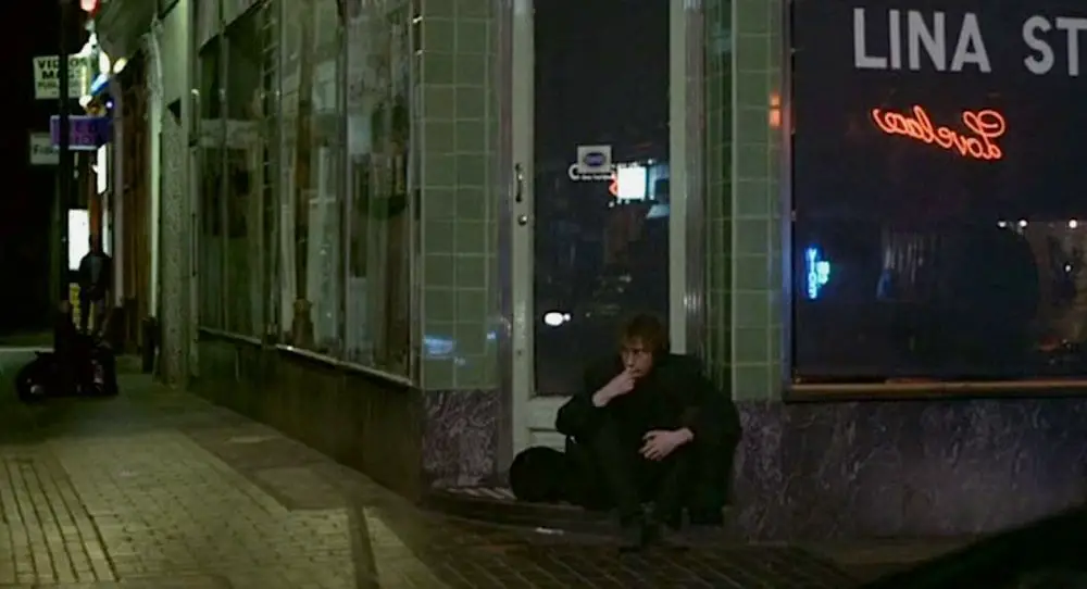 Johnny sits by himself at night outside a closed shop