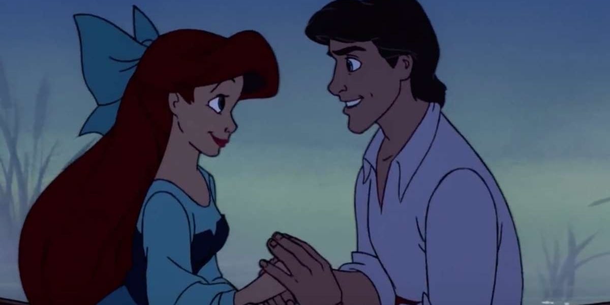 Ariel and Eric sitting across from one another, holding hands and smiling at one another in The Little Mermaid