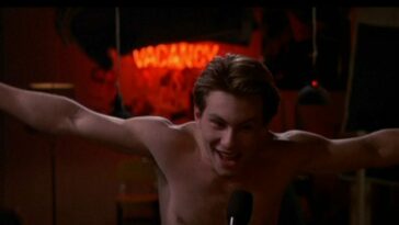 Shirtless Christian Slater yelling into a microphone
