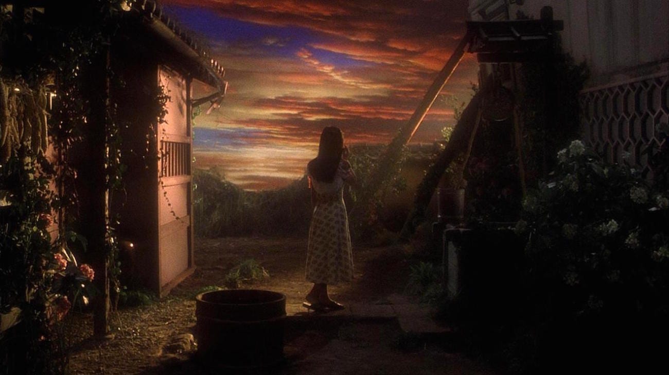 The character of Fantasy admires the painted sky as she stands next to the well.