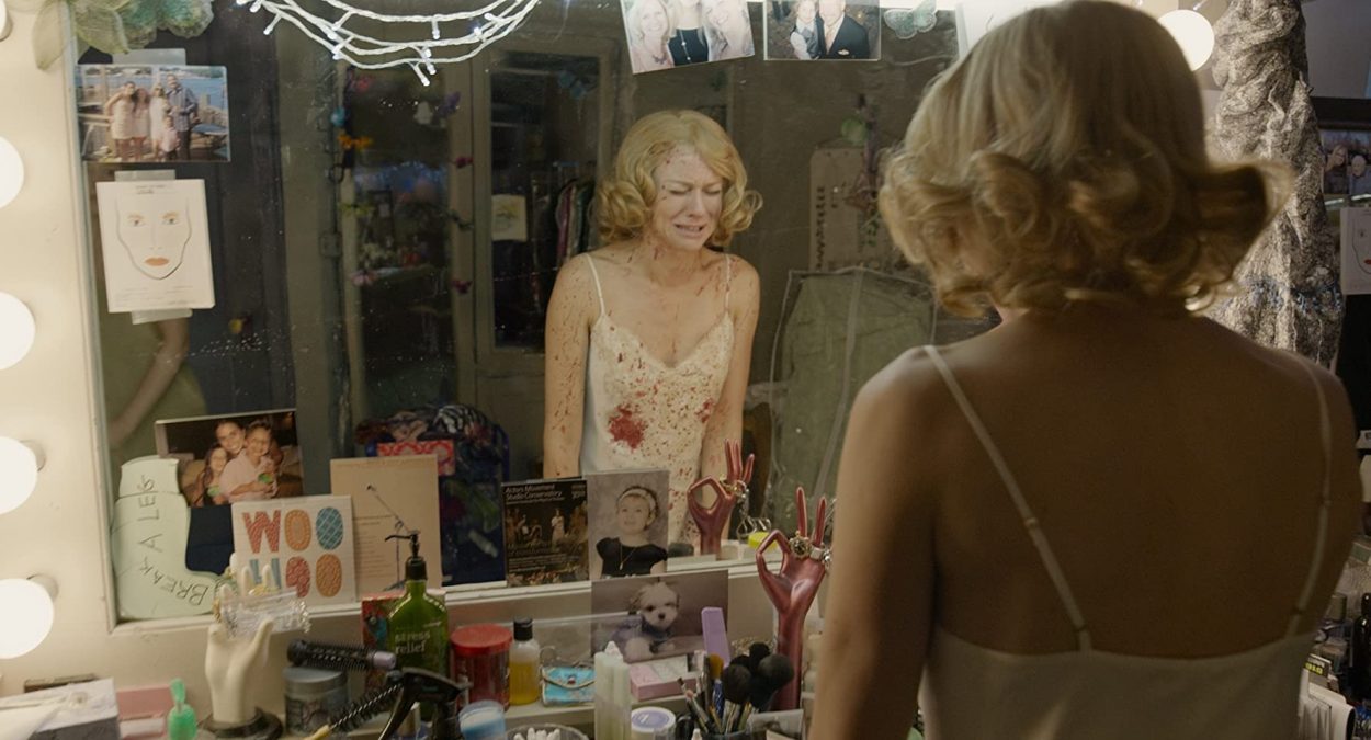 Leslie wears a blood-splattered negligee and sobs in her dressing room mirror.