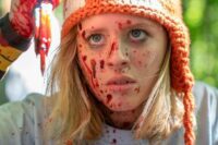 A blood-soaked Becky holds up a cluster of colored pencils used to stab someone.
