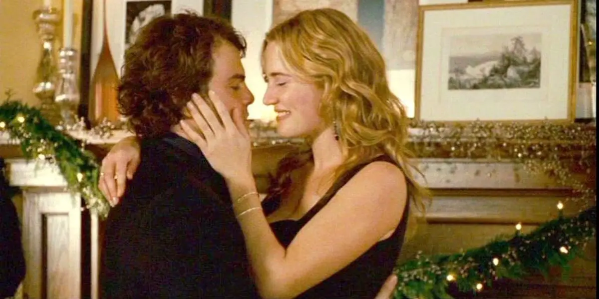 Kate Winslet and Jack Black facing one another, Kate with her hand on Jack's cheek and smiling at him as they stand in a living room in The Holiday