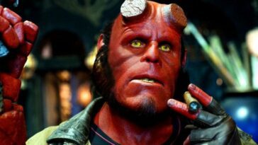 A close up shot of Hellboy with his Samaritan pistol on his left hand and a lit cigar in his right