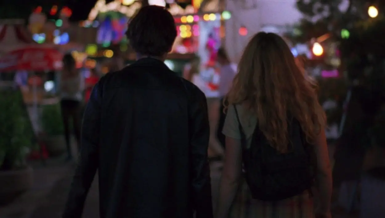 Jesse and Celine, shown from behind, walking through the amusement park.