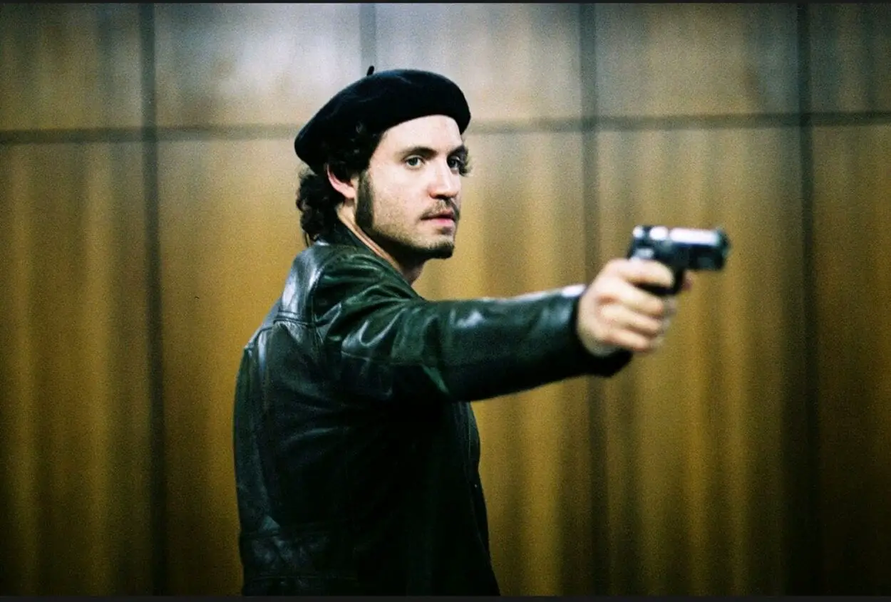 Carlos aims a handgun at offscreen hostages during the OPEC meeting