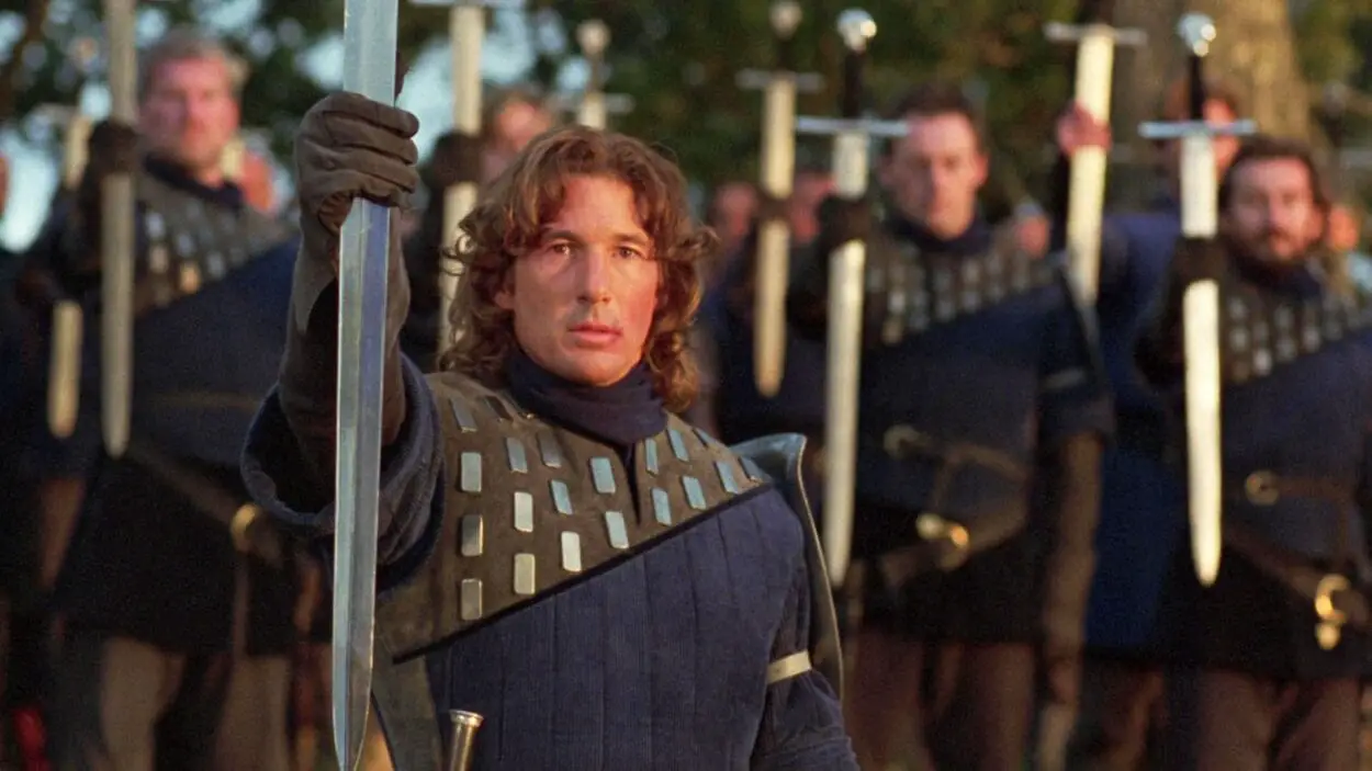 Lancelot holds up a sword in salute at a lakeside funeral.