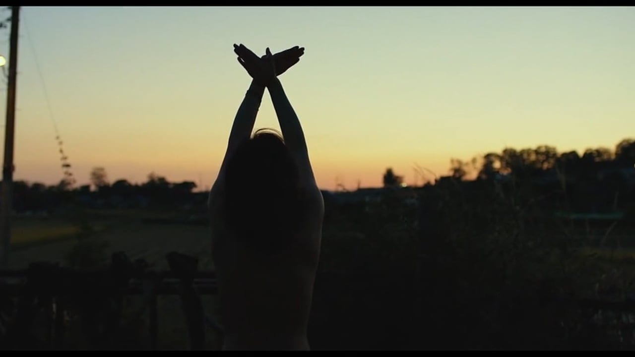 Haemi raises her arms to the sky, facing the sunset.