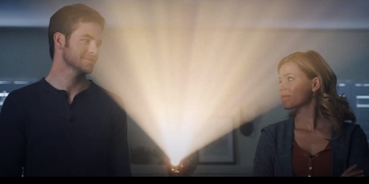 Sam and Frankie looking at each other warmly, Frankie a bit teary-eyed, with a projector light shining between them in the ending of People Like Us