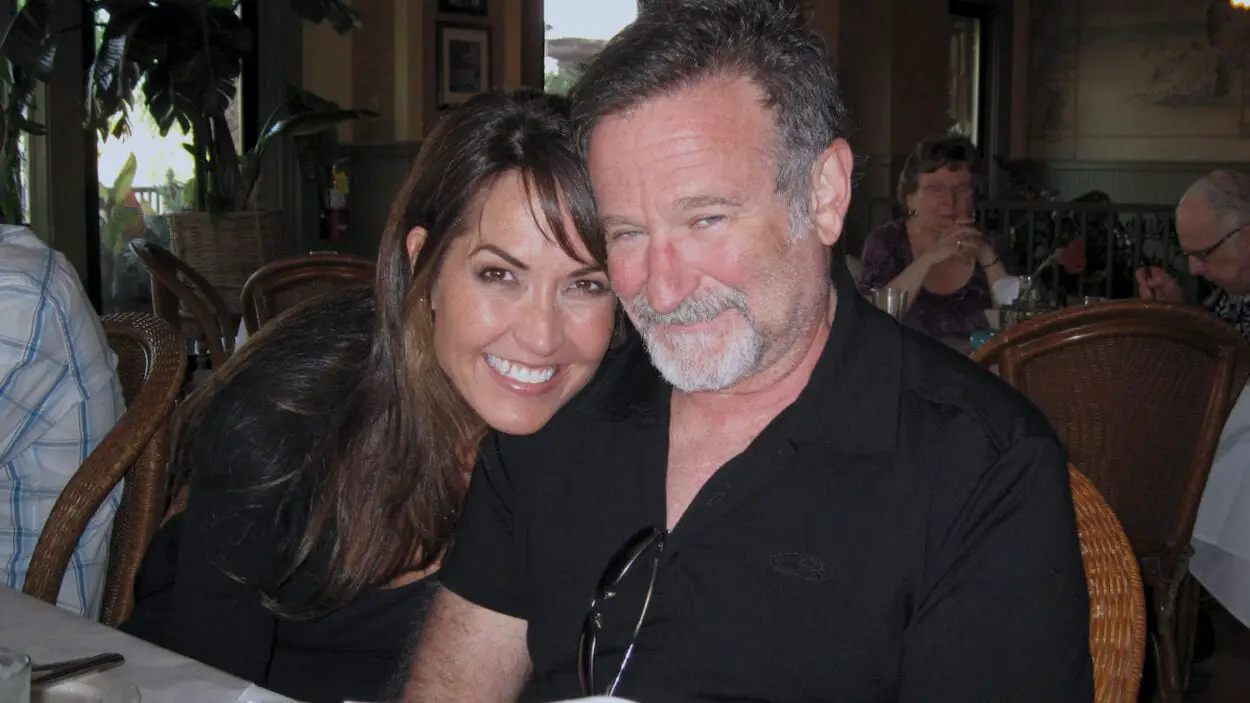 Susan Schneider Williams and Robin Williams pose for a photo, smiling.