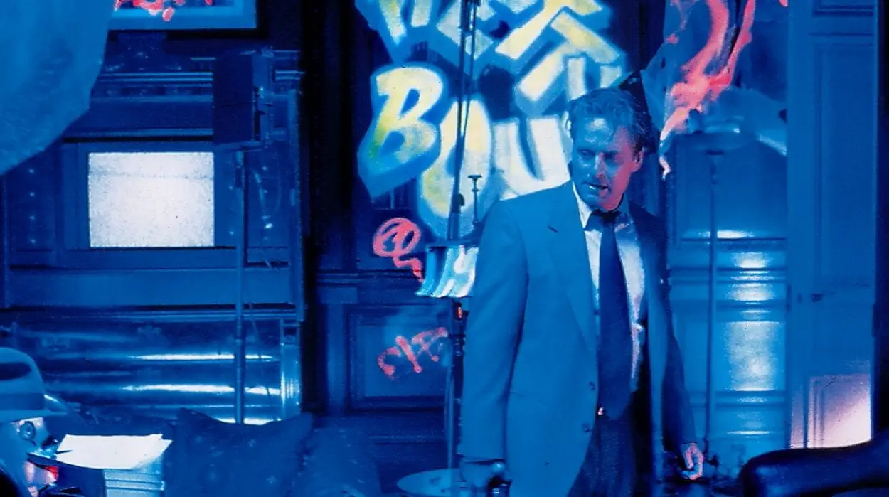 Nicholas Van Orton stands in a strange blue lit graffiti covered room