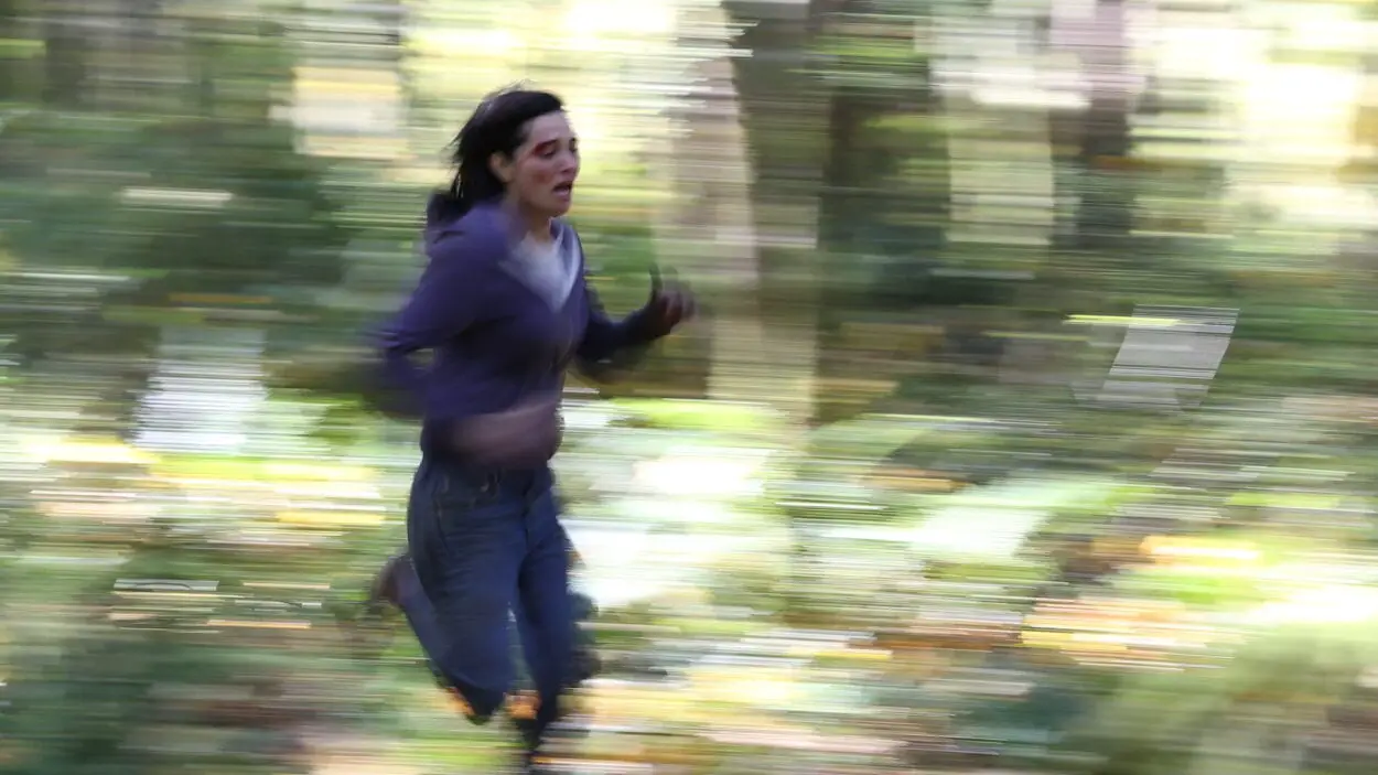 Jessica (Jules Wilcox) running through the woods. The photo is blurred to indicate speed.