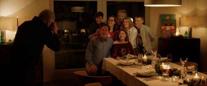 Paul steps back to take a family picture at dinner with everyone around Lily.
