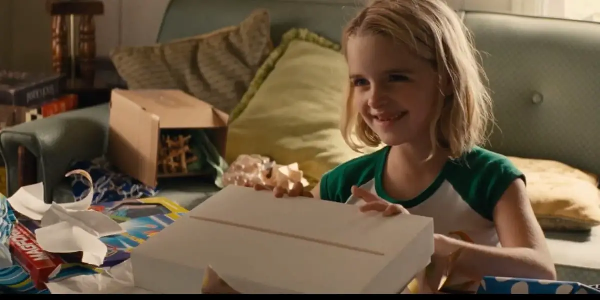 Mary happily opening gifts with a smile, a couch in the background, in Gifted