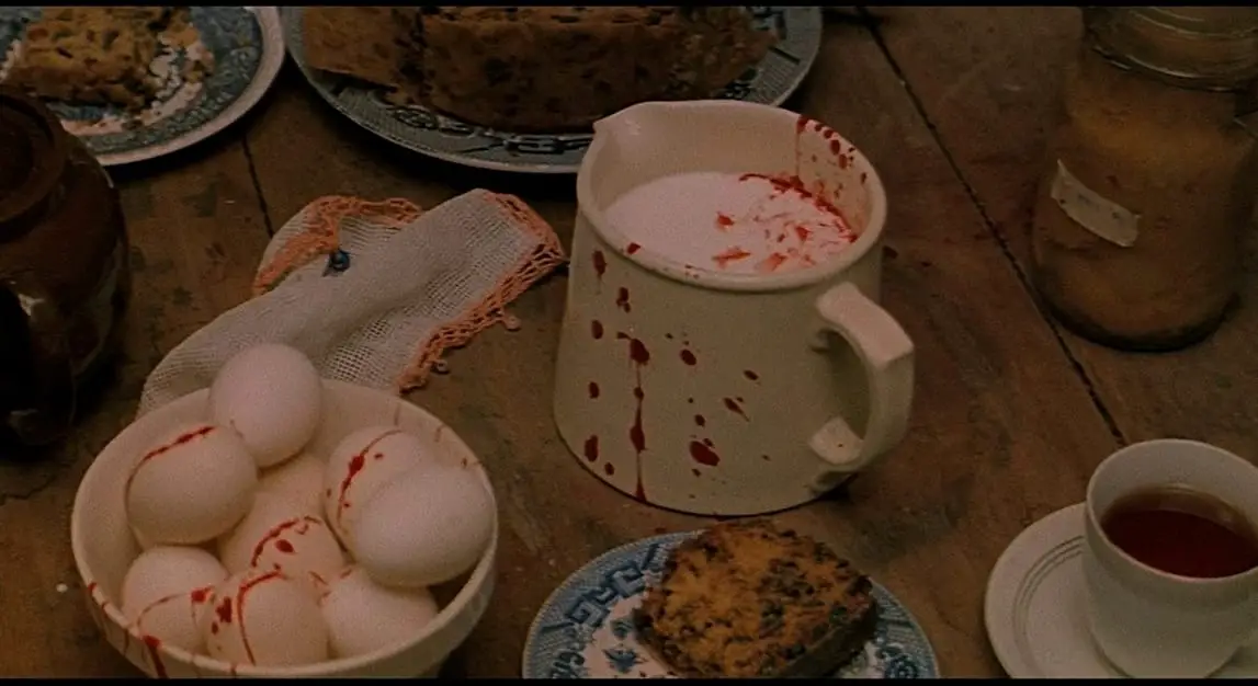 A dinner table that has eggs in a bowl and milk in a coffee cup is splattered with blood.