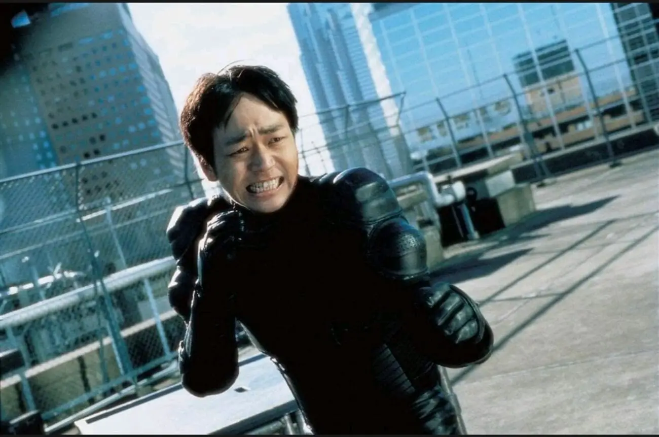 A dutch angle medium-shot of a grimacing Ichi (Nao Ohmori) as he holds his fists to fight
