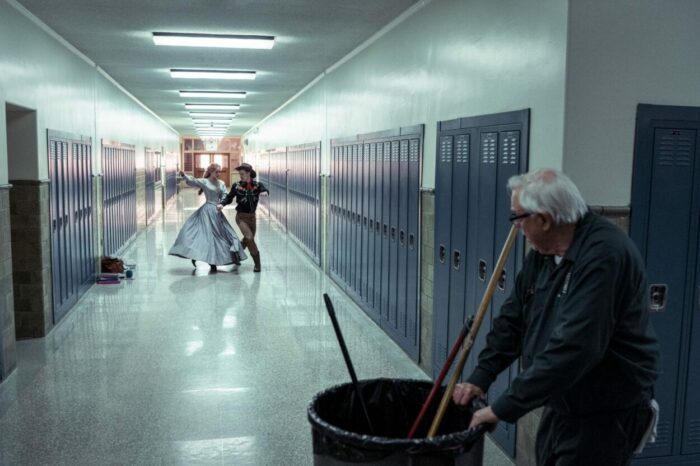 A pair of dancers perform in front of a school janitor.