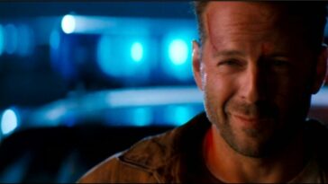 Bruce Willis smiling in front of police cars