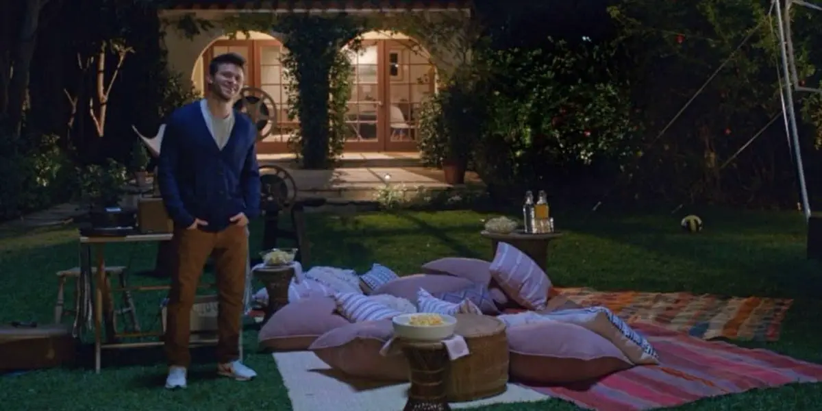George standing besides a bunch of pillows ready for movie night in Home Again