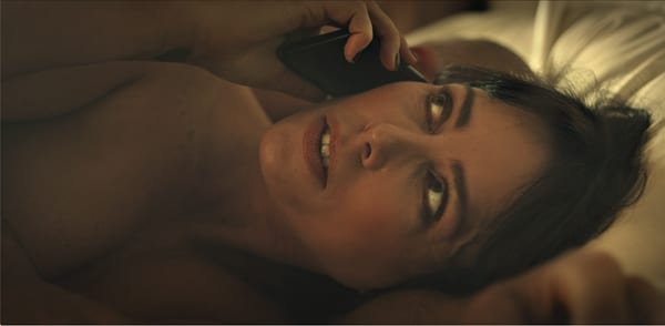 Sarah receives a surprise call from her husband while in her lover's bed