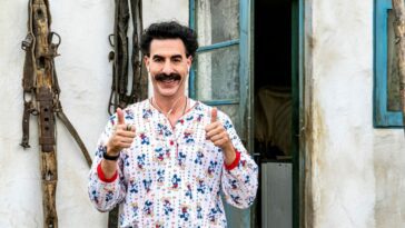 Borat raises two thumbs up while wearing pajamas and an iPod.