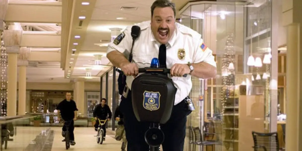 Paul Blart being chased by thugs in a mall while riding a Segway 
