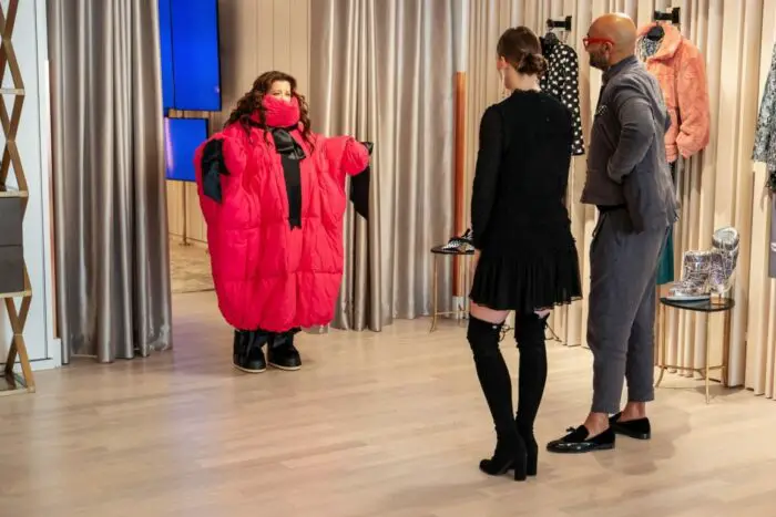 Carol tries on a ridiculous red puffy outfit in front of two boutique managers