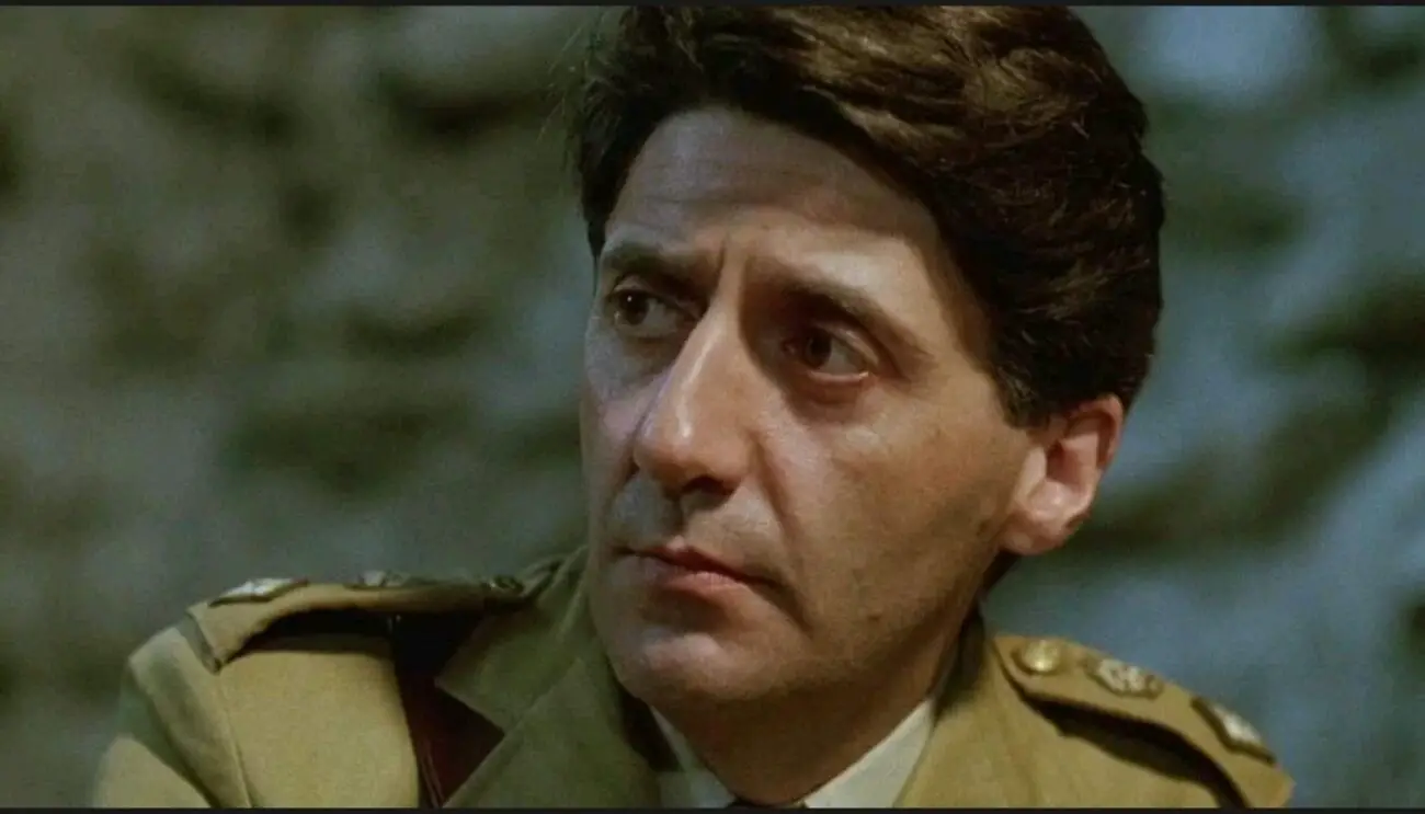 A medium shot of Colonel Lawrence (Tom Conti) looking towards the left of the camera frame.
