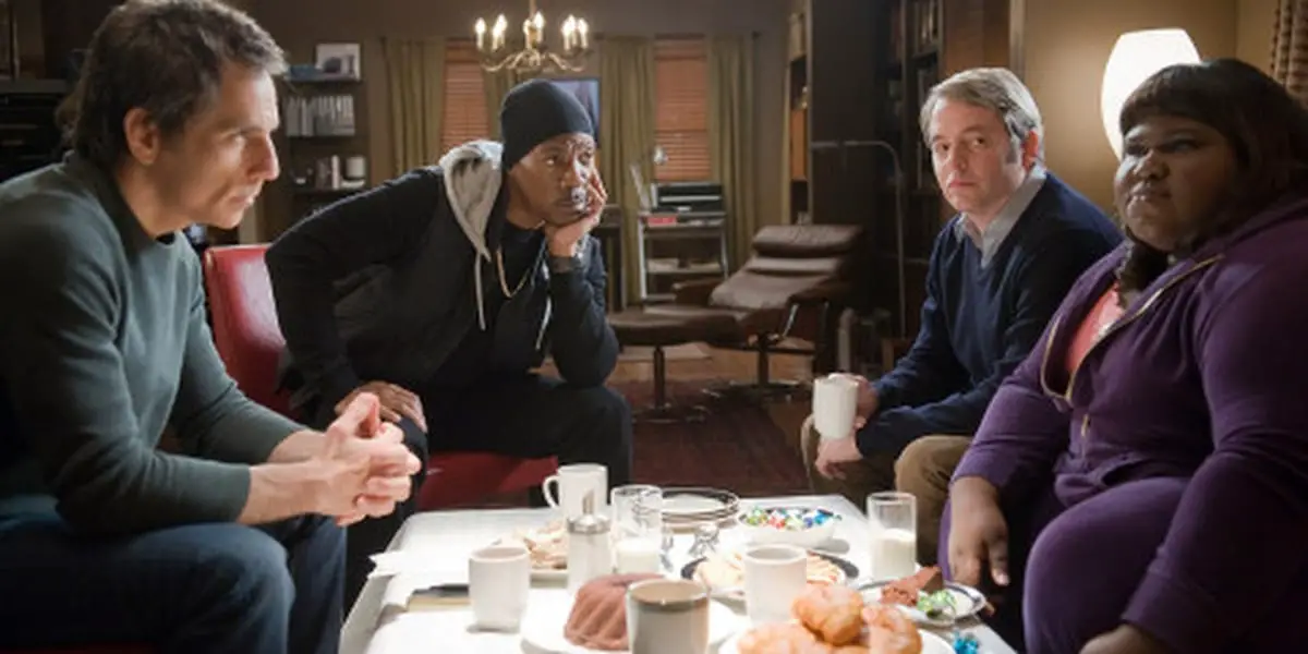 Ben Stiller, Eddie Murphy, Matthew Broderick, and Gabourey Sidibe sitting around a table in an apartment as their characters in Tower Heist