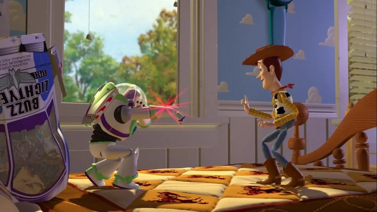 Buzz and Woody meet on Andy's bed, with Buzz (left) aiming his laser at Woody (right), who is attempting to calm Buzz down. Buzz's spaceship packaging lies crumpled behind him.