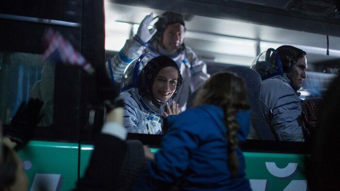 Sarah waves goodbye to her daughter from a bus before boarding her rocket.
