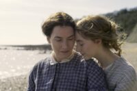 Charlotte (Saoirse Ronan) snuggles up to Mary(Kate Winslet) on the Beach in a still from "Ammonite"