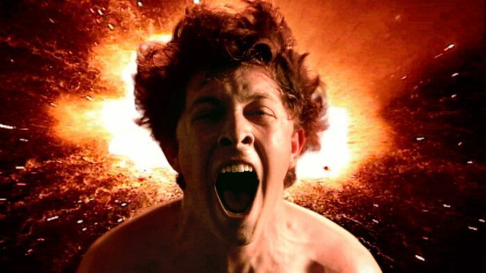 Archie, a boy with wild brown hair, facing the camera and screaming. Behind him is an image of an explosion.