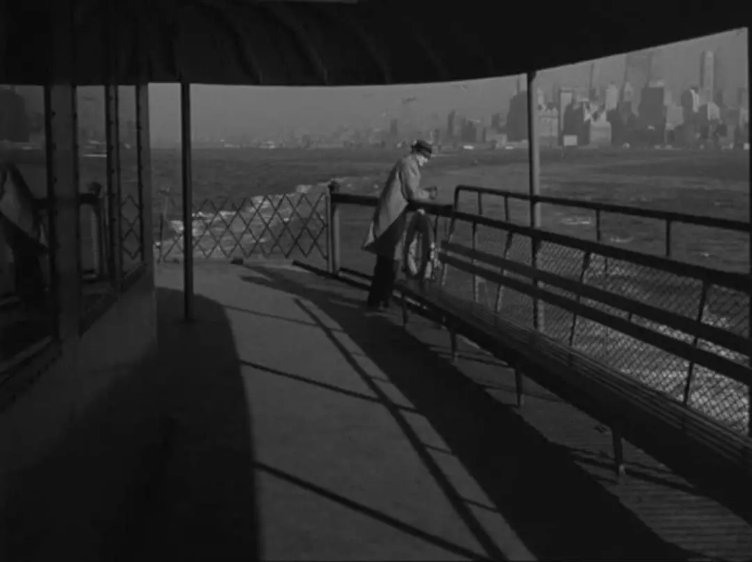 Still from Blast of Silence. Frankie Bono stands alone on the Staten Island Ferry. The New York City skyline looms in the distance.