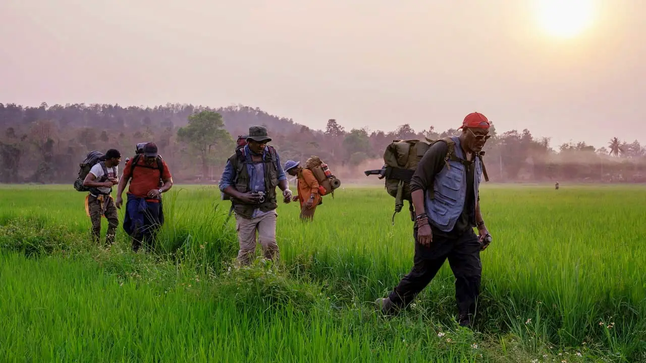 A group of men walk across a green field in Vietnam