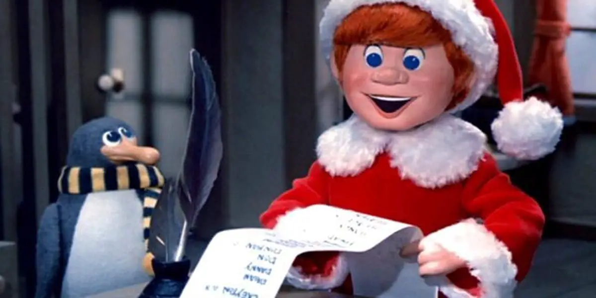 Kris Kringle holding a list, with Topper the penguin, in Santa Claus is Comin to Town