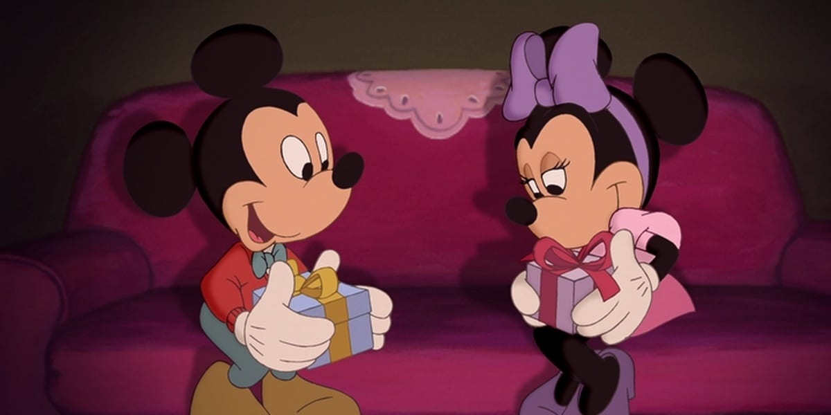 Mickey and Minnie holding presents, smiling, sitting on a couch in Mickey's Once Upon A Christmas