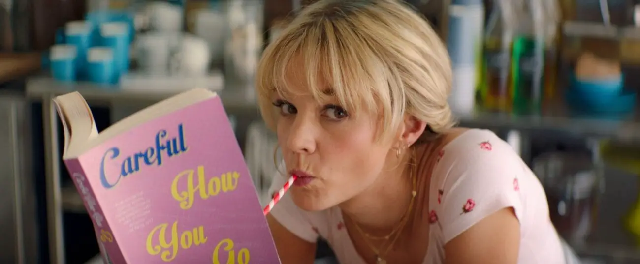 Cassie looks over from her book with a straw in her mouth.